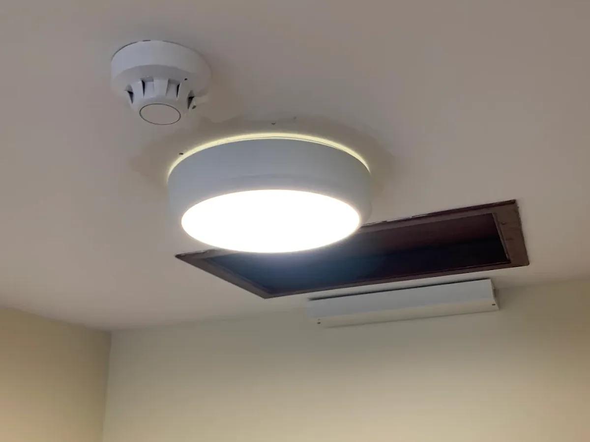 LED bulkhead light installed next to an interlinked smoke detector on a ceiling