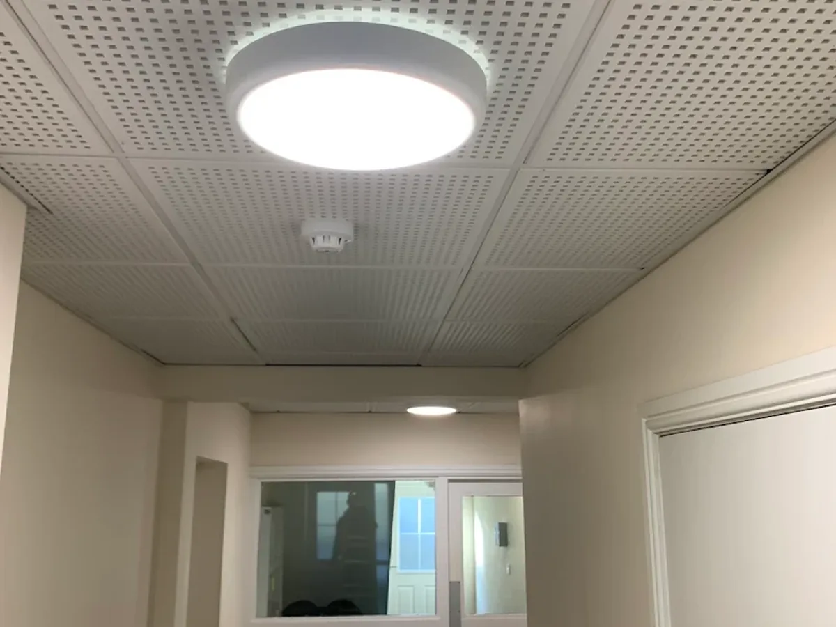 Circular LED bulkhead lights installed in a communal corridor ceiling