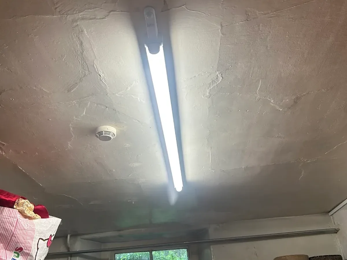 LED batten light fitting installed on an older ceiling with a smoke detector