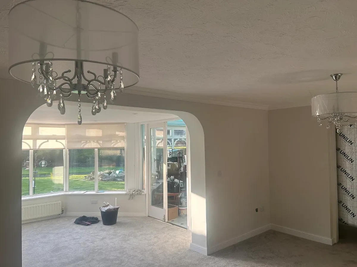 Living room with pendant ceiling light and archway through to a conservatory