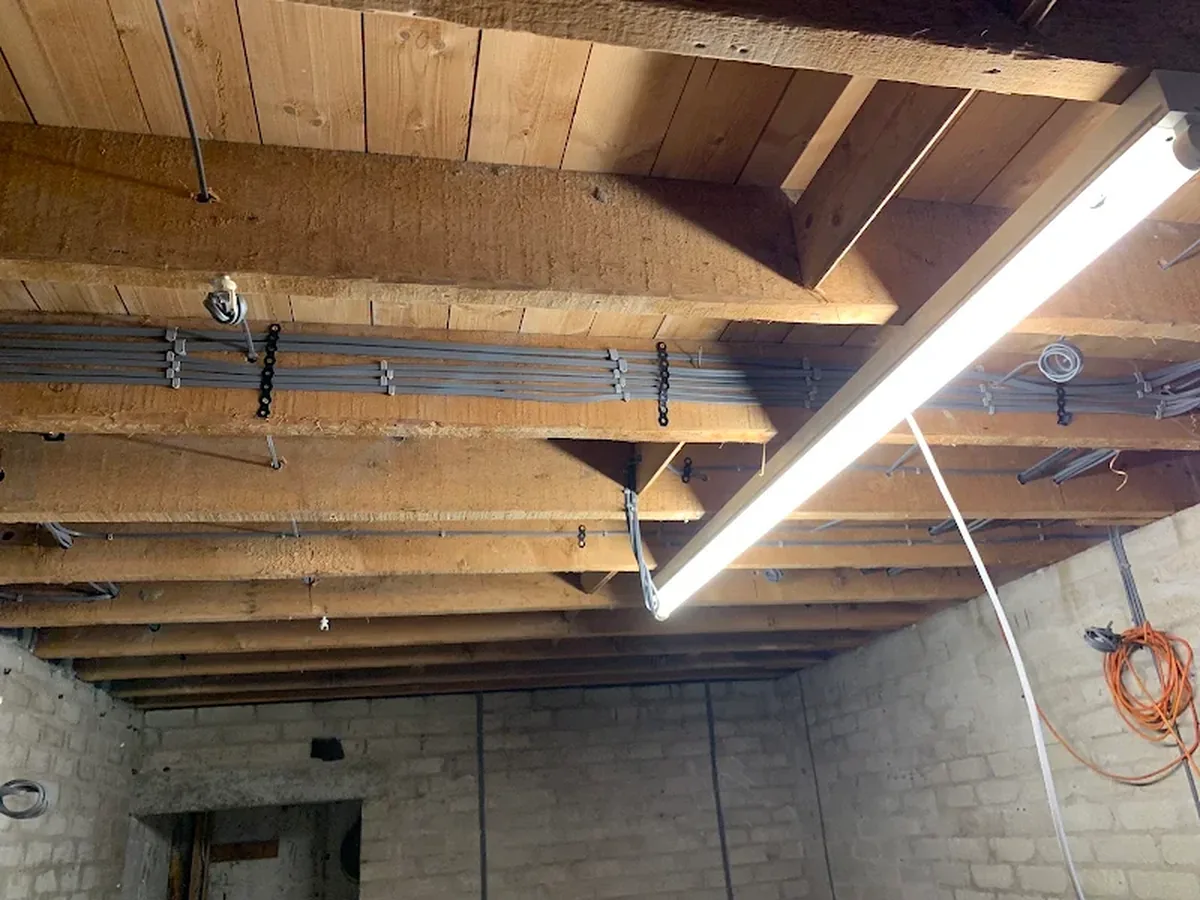 Electrical cables clipped through exposed ceiling joists during a rewire first fix