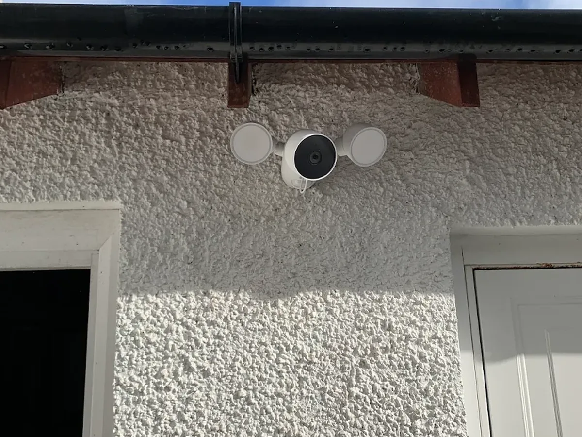 Security floodlight with integrated camera installed above an external doorway
