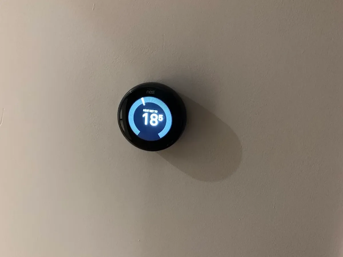Smart room thermostat installed on a wall showing the current temperature